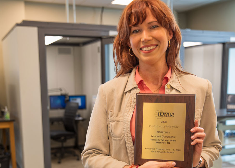 Woman with red hair holding a volunteer award plaque.