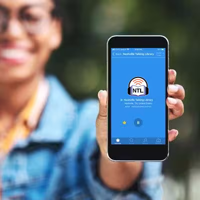 Woman holding a phone showing the talking library in the Simple Radio app on an iPhone.